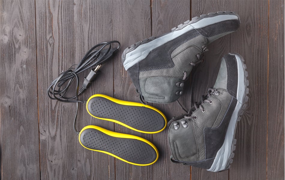 Pair of leather hiking boots sitting in the snow, representing cold and wet outdoor conditions.