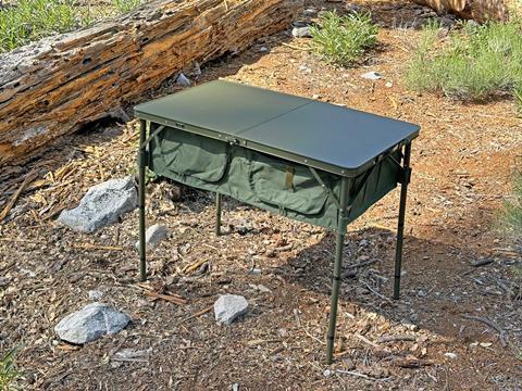 The DOD Outdoors Good Luck Table featuring integrated nylon storage shelves underneath.