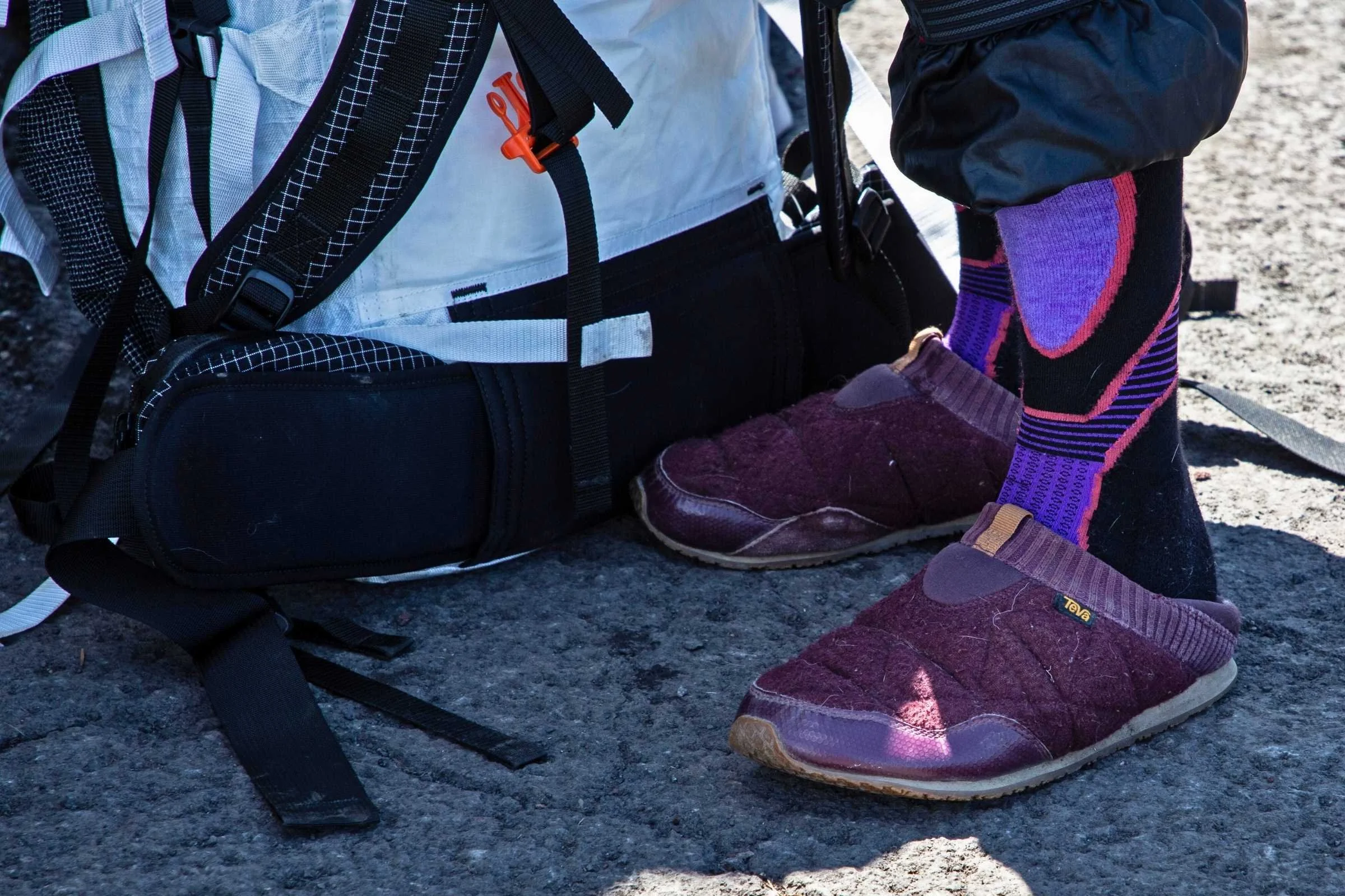 A person wearing quilted Teva ReEmber slip-ons while standing near a vehicle in a snowy setting.