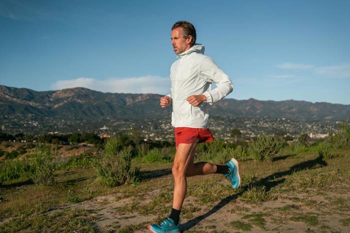An athlete running on a scenic paved path wearing technical gear.