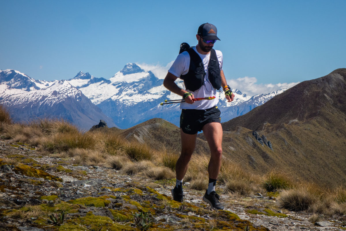 A runner on a scenic mountain trail wearing a Salomon ADV Skin 12 vest.