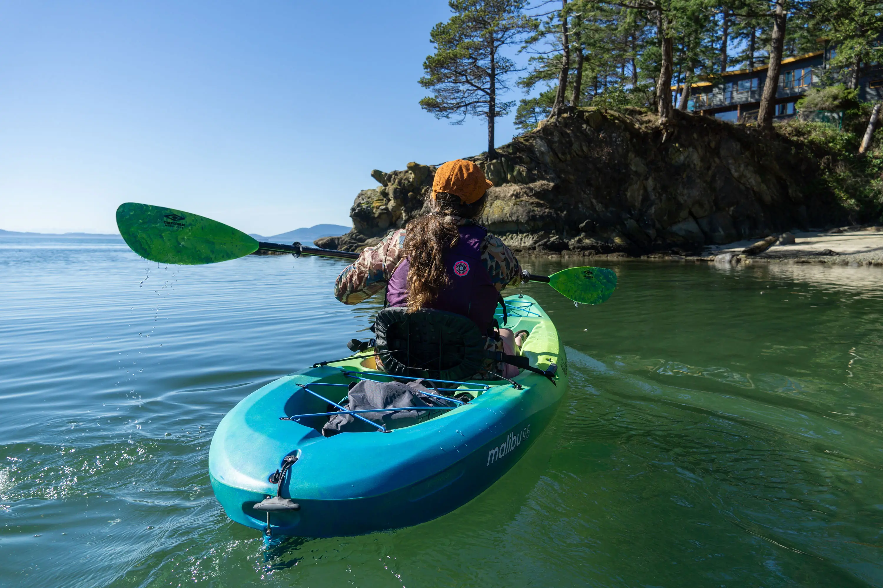 A paddler testing a beginner kayak on a calm, scenic lake.