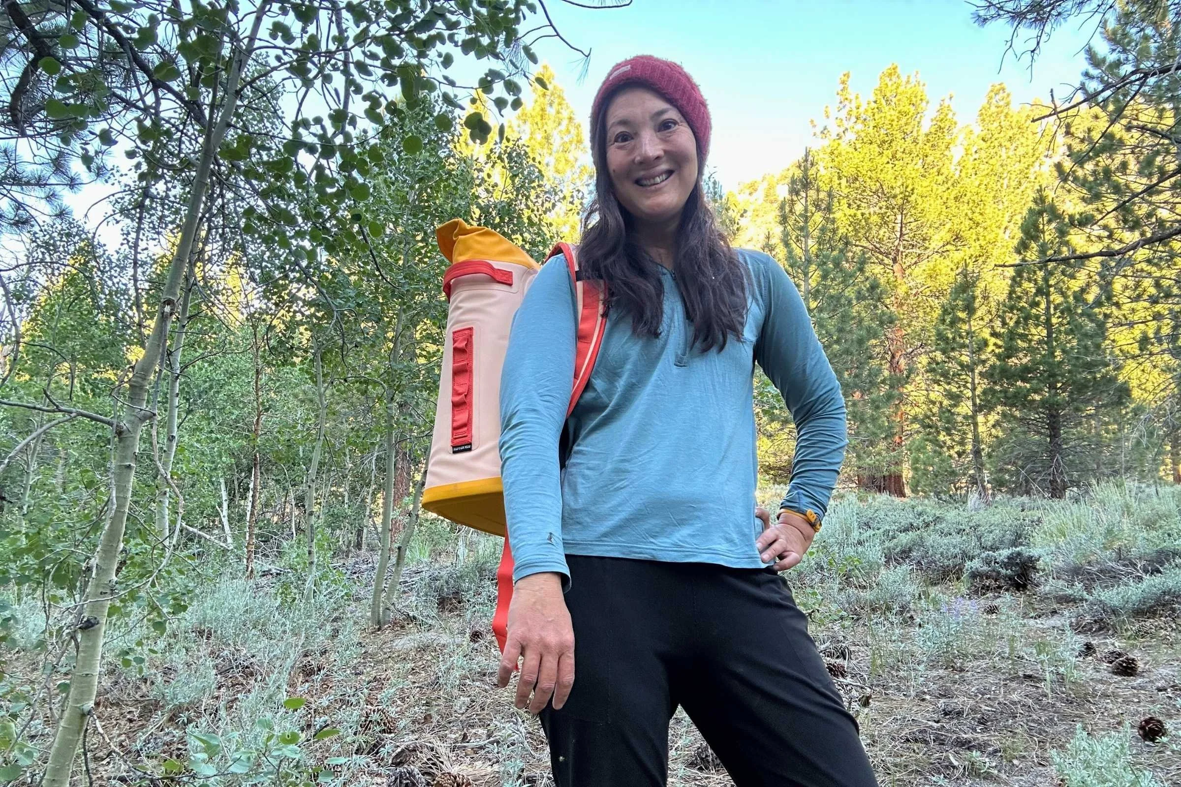 A hiker walking on a trail wearing a grey YETI M20 backpack cooler.