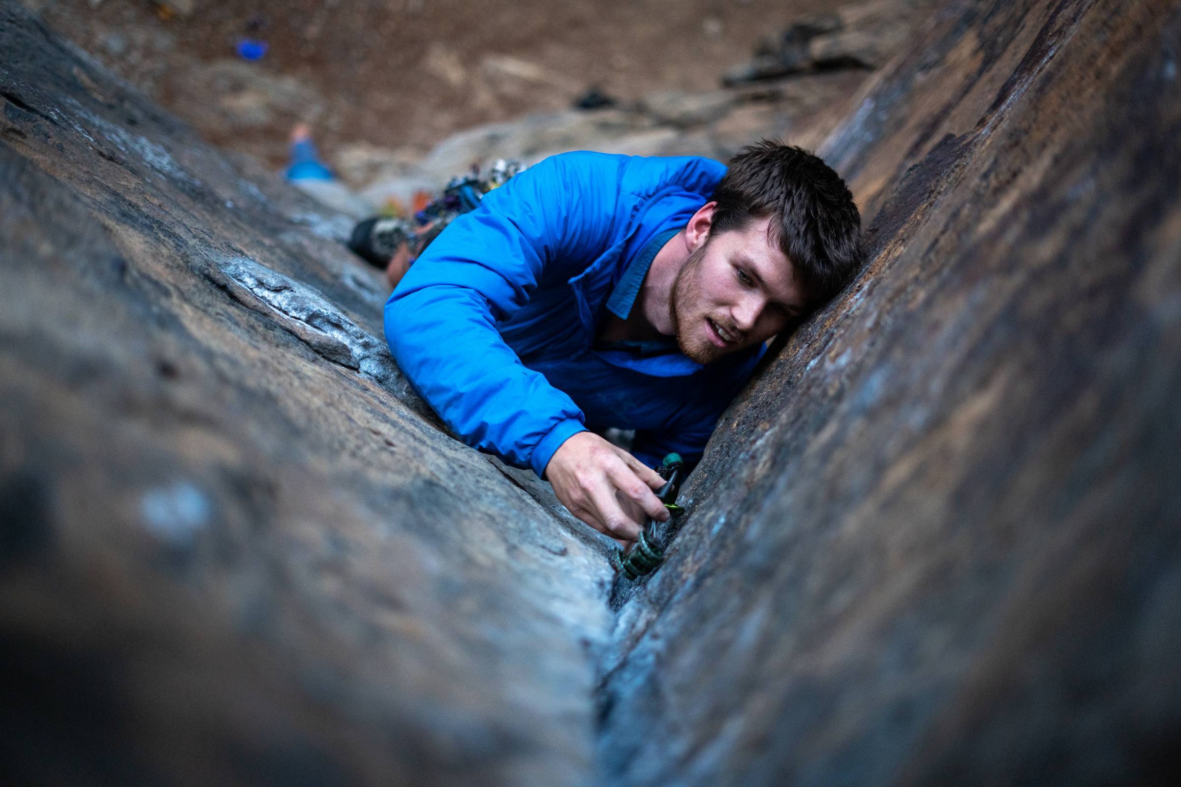 A hiker wearing an Arc'teryx Atom Hoody while walking through a forest