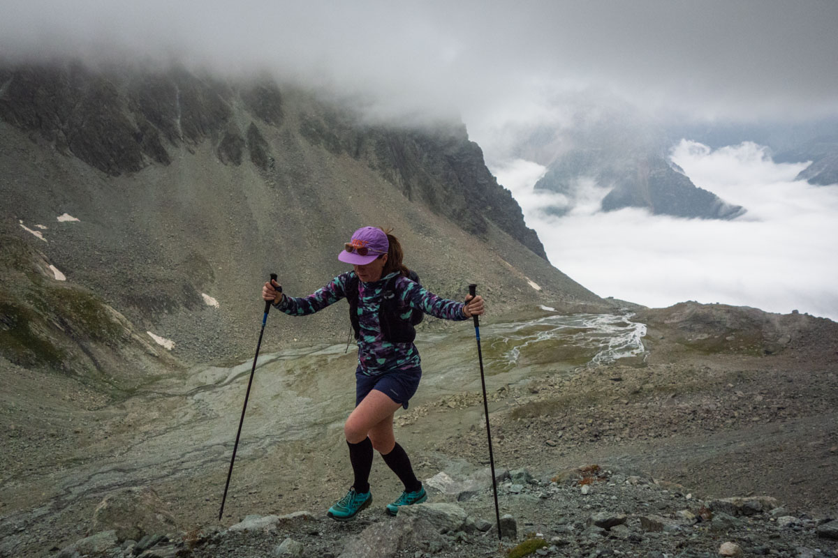 A hiker using carbon fiber trekking poles on a high-altitude trail in the Italian Alps.