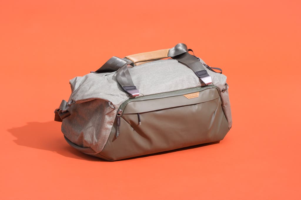 Sage-colored Peak Design Travel Duffel on orange background.