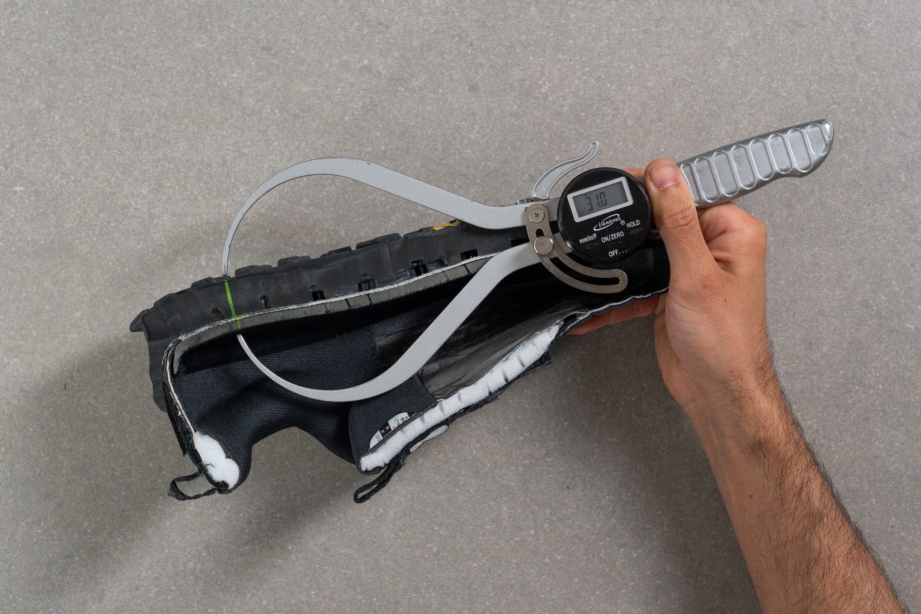 A digital caliper measuring the heel stack height of the Altra Olympus 6.