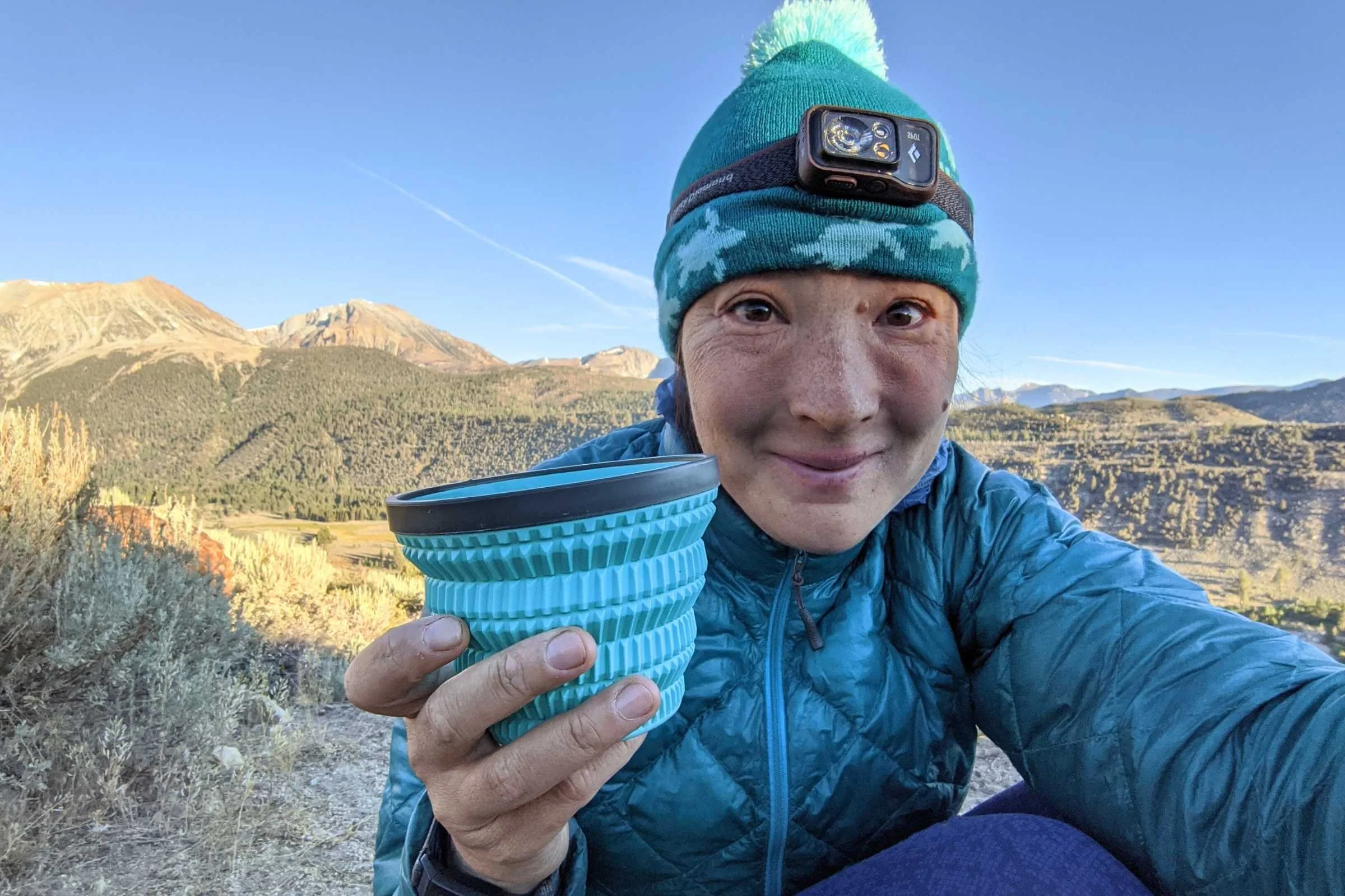 A hiker wearing the Black Diamond Spot 400 while sitting at a campsite at night.