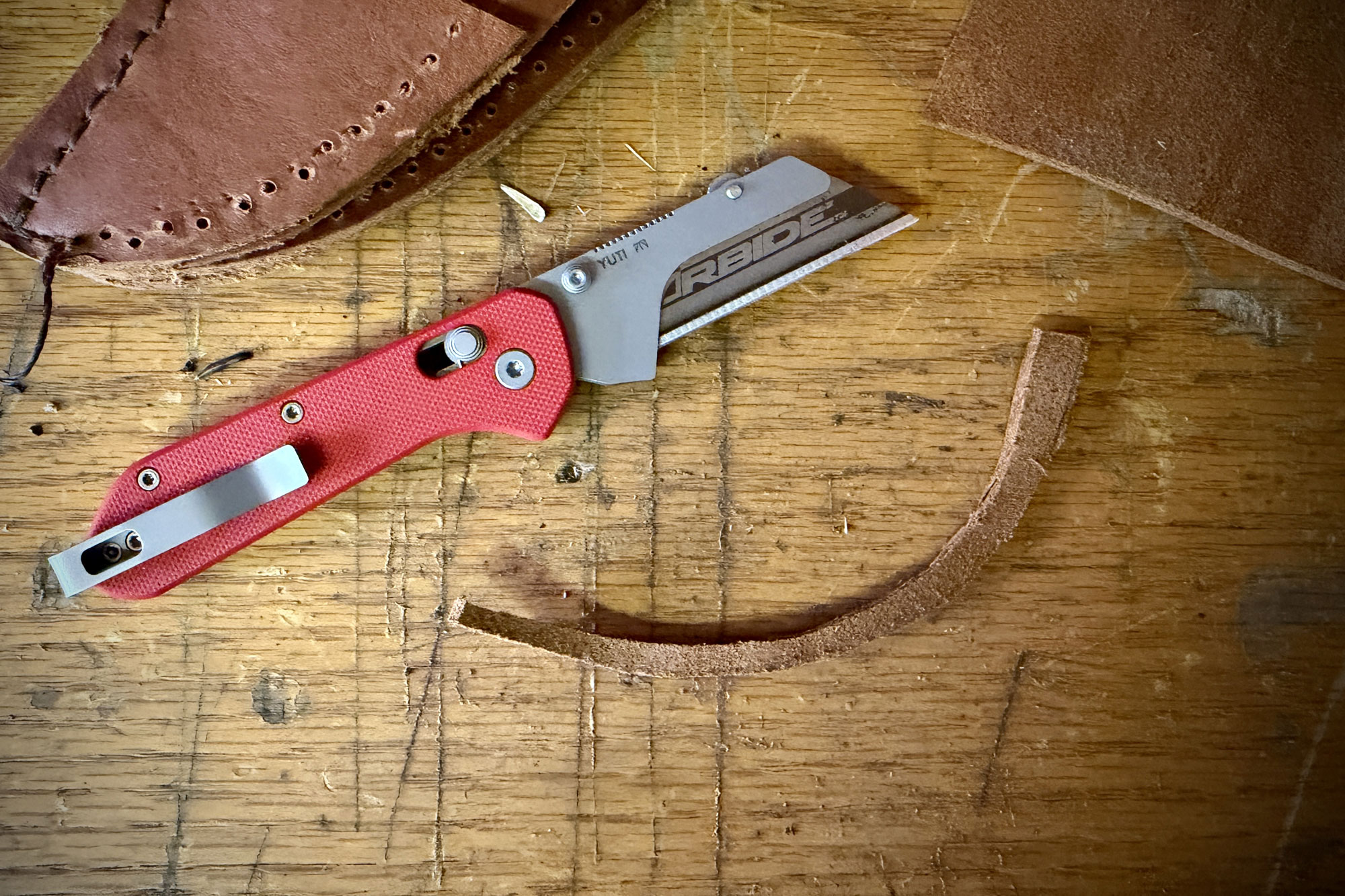 Knafs Yuti knife on a wood surface focusing on the T8 thumb screw.