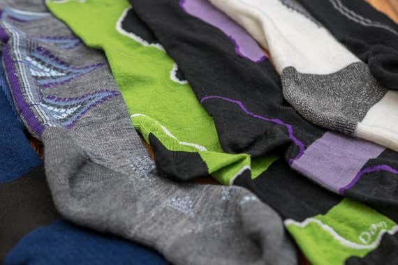 Dozens of pairs of colorful ski socks laid out on a table for side-by-side comparison.