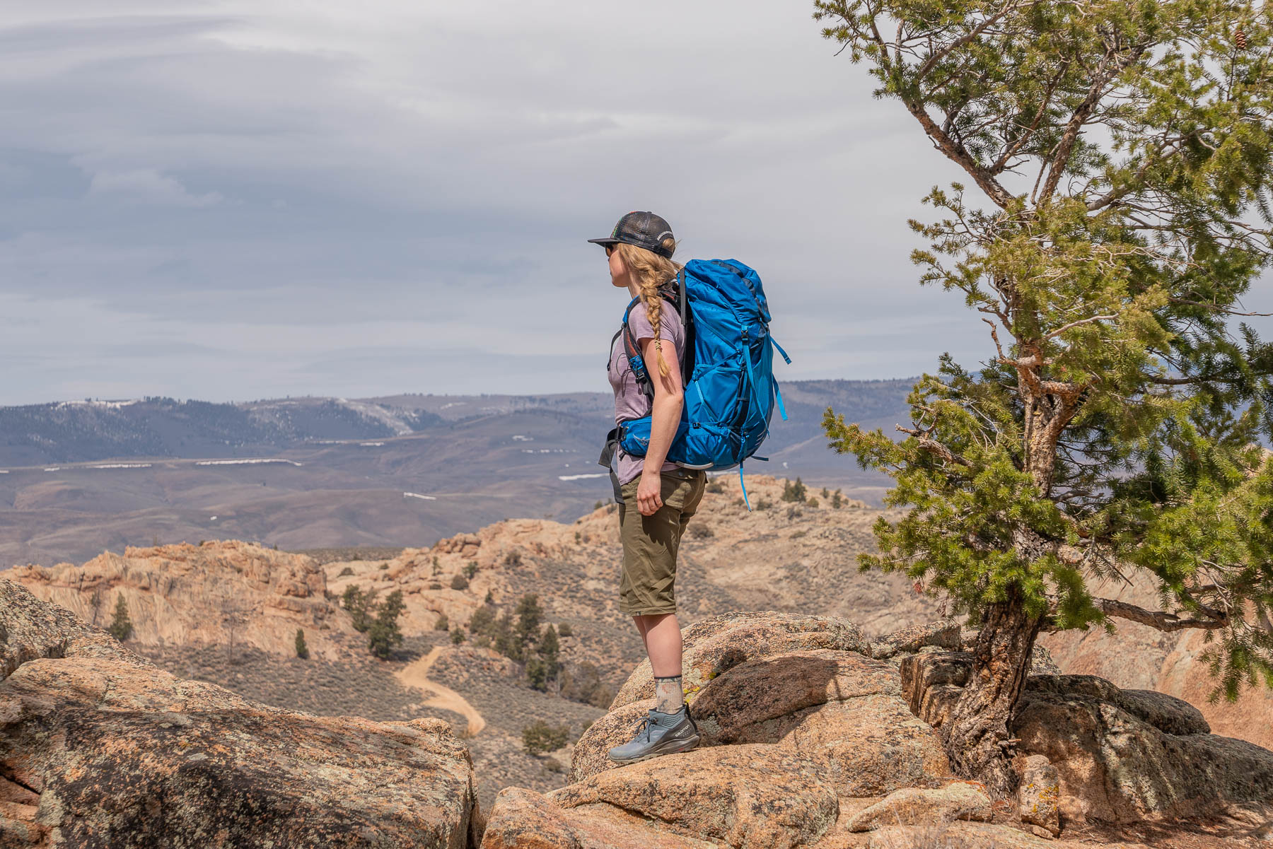 Two female hikers trekking up a scenic mountain ridge with backpacks.