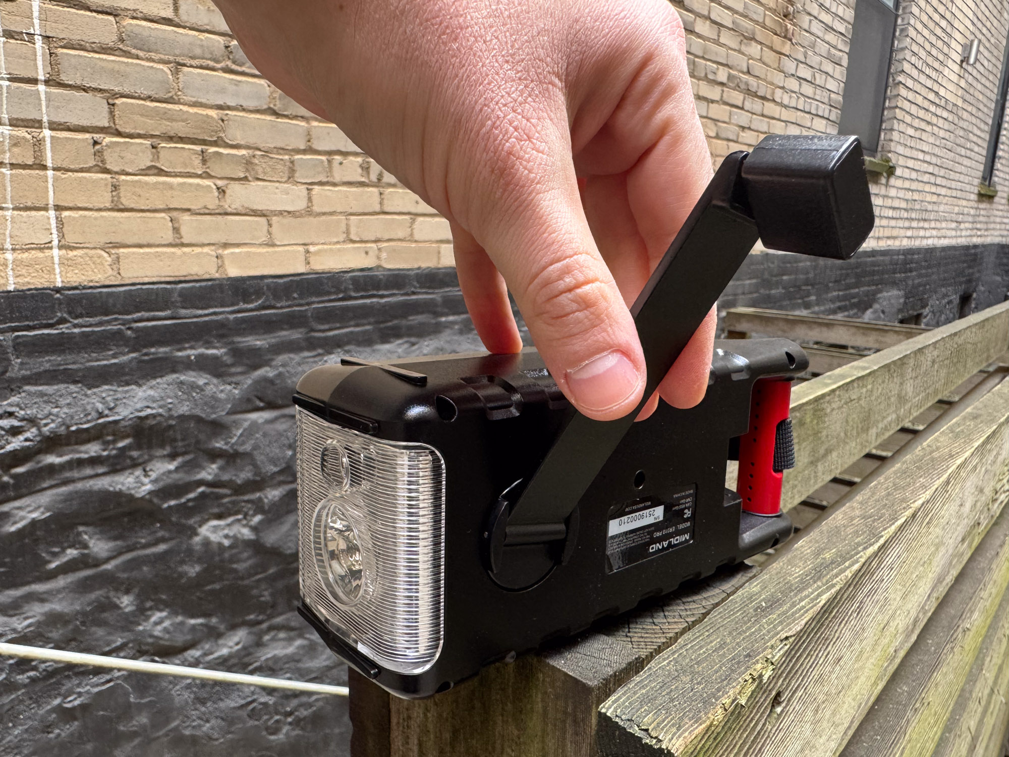 A person demonstrating the hand crank on the Midland weather radio.