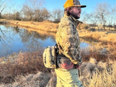 The KUIU DeltaStorm 800 being tested for water resistance while a person wades through deep water.