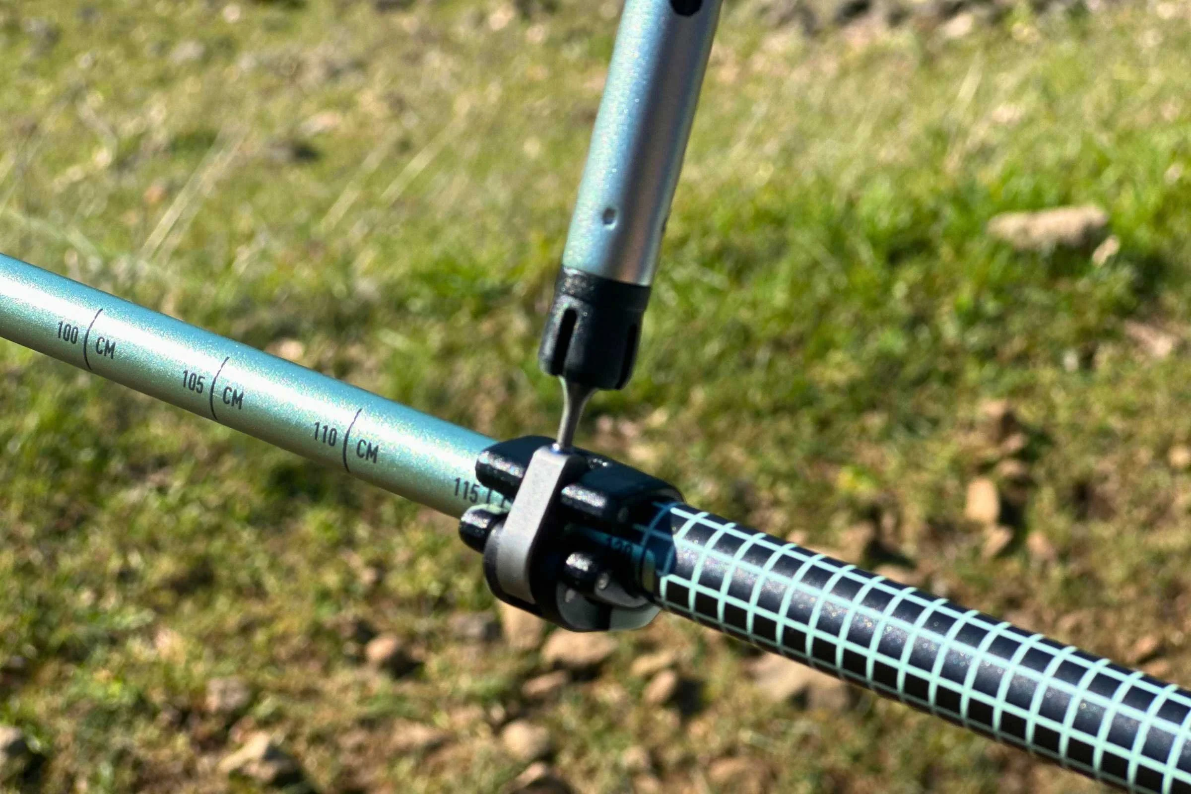 Close-up of hands using a small tool to adjust the FlickLock mechanism on a Black Diamond trekking pole.