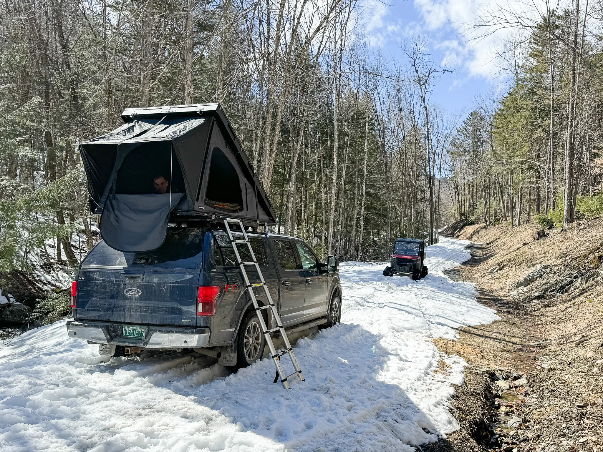 Close-up of the metal mounting brackets and bolts securing a rooftop tent to a heavy-duty roof rack.
