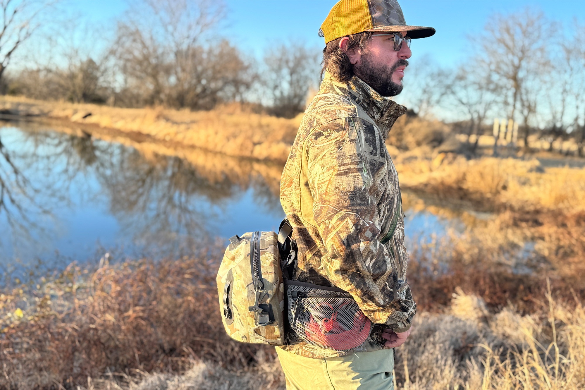 A person wearing the KUIU DeltaStorm 800 waistpack standing near a body of water.