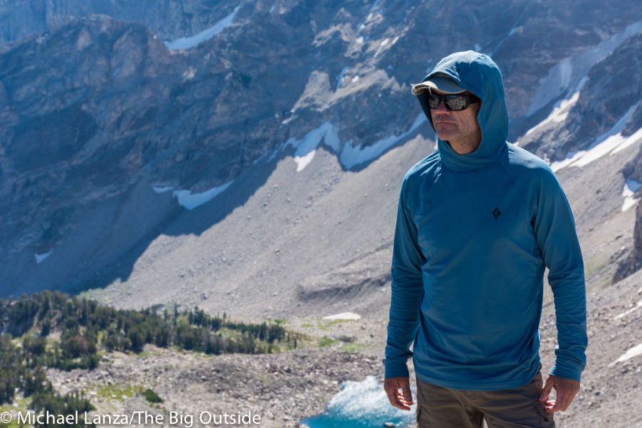 A climber using the Black Diamond Alpenglow Hoody for protection while scaling a rock face.