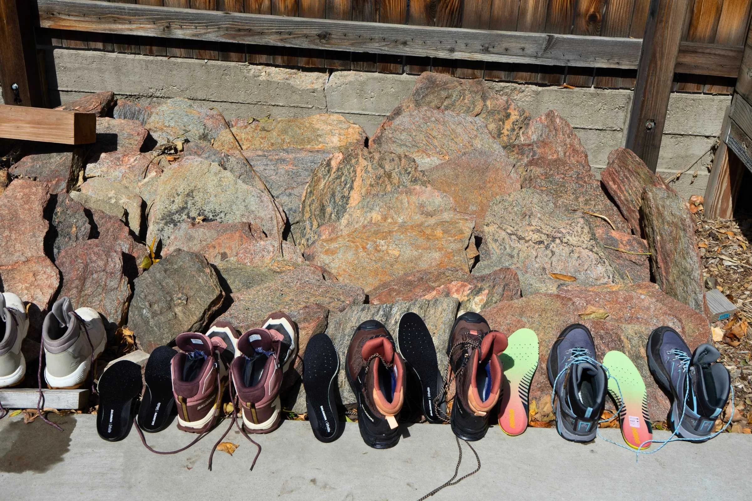 A large variety of women's hiking boots lined up on a wooden floor.