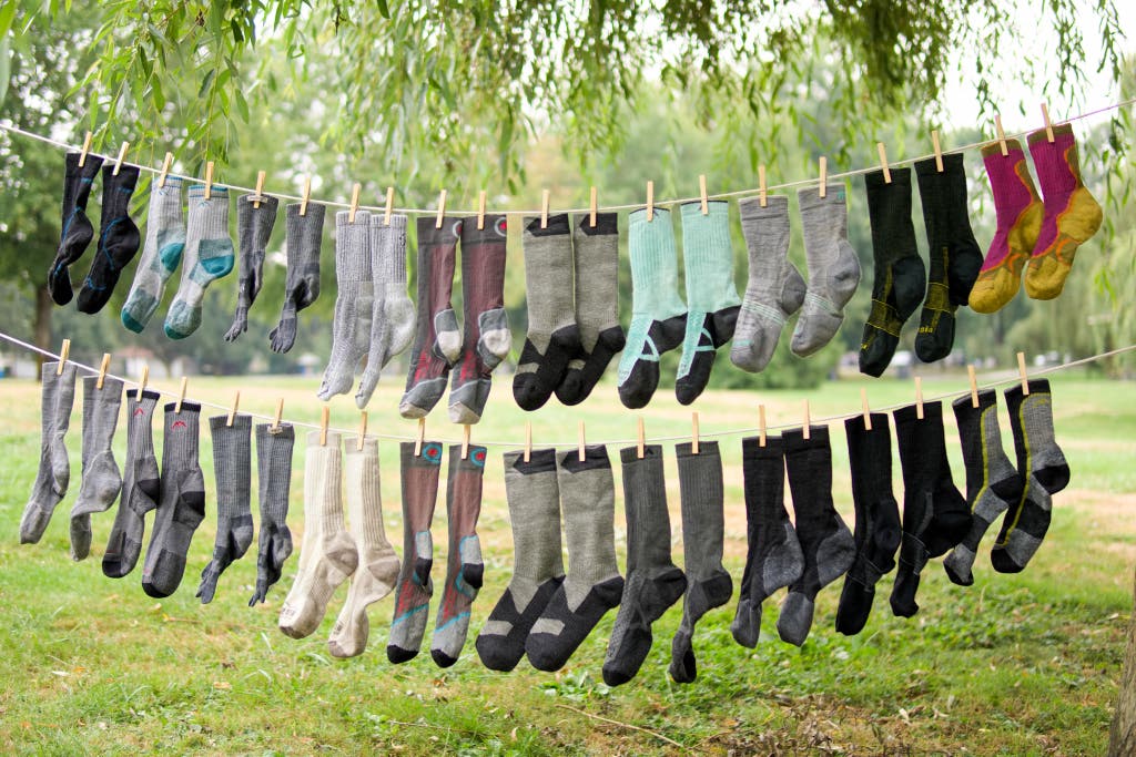 A large collection of colorful hiking socks hanging on a clothesline for outdoor testing