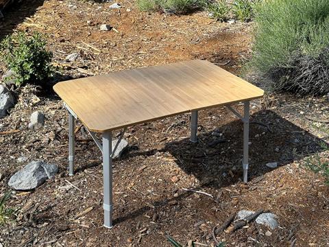 The Dometic GO Compact Camp Table with a natural bamboo tabletop and adjustable legs.