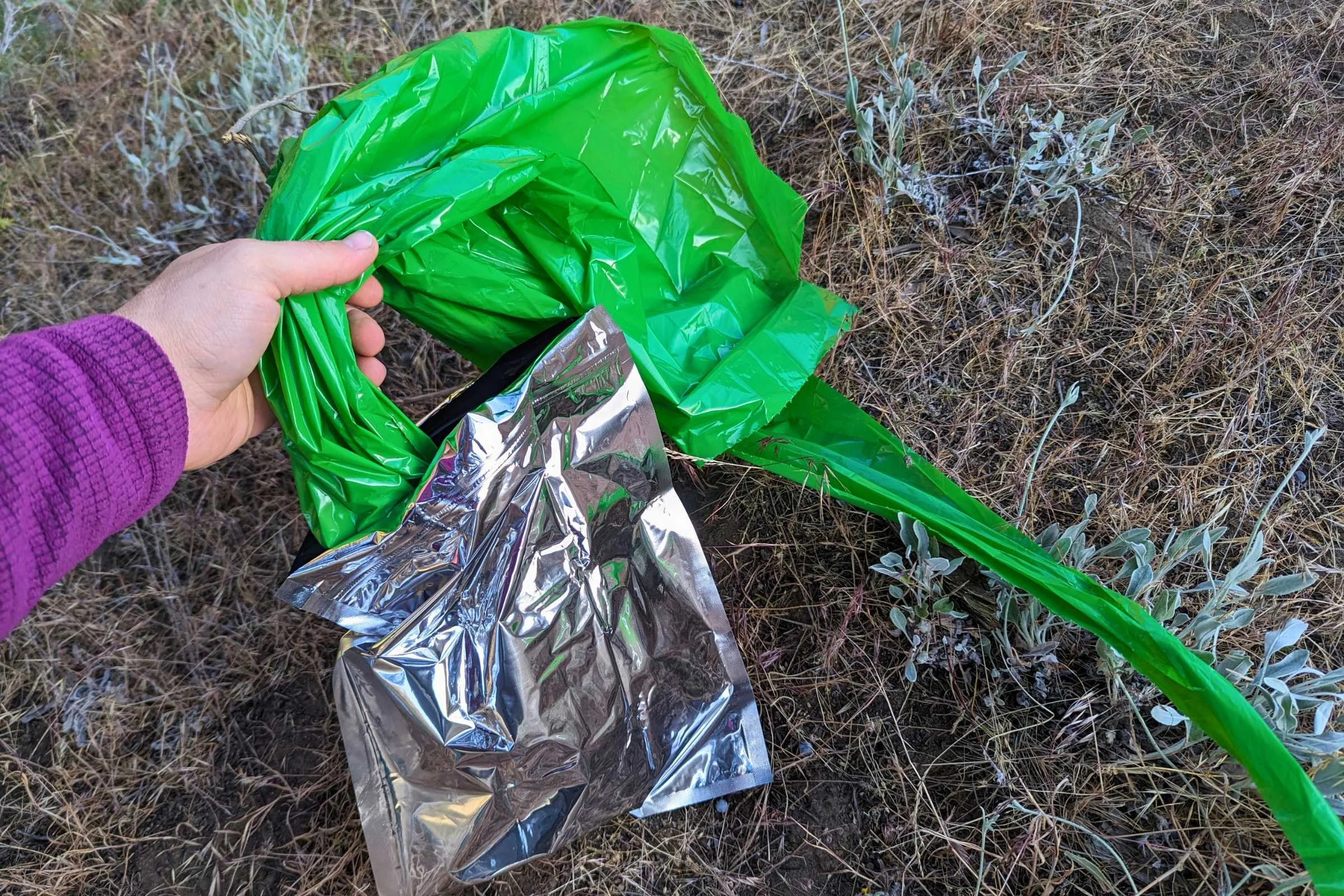 A hand tying off the inner bag of a Biffy Bag kit before sealing it in the outer Mylar bag.