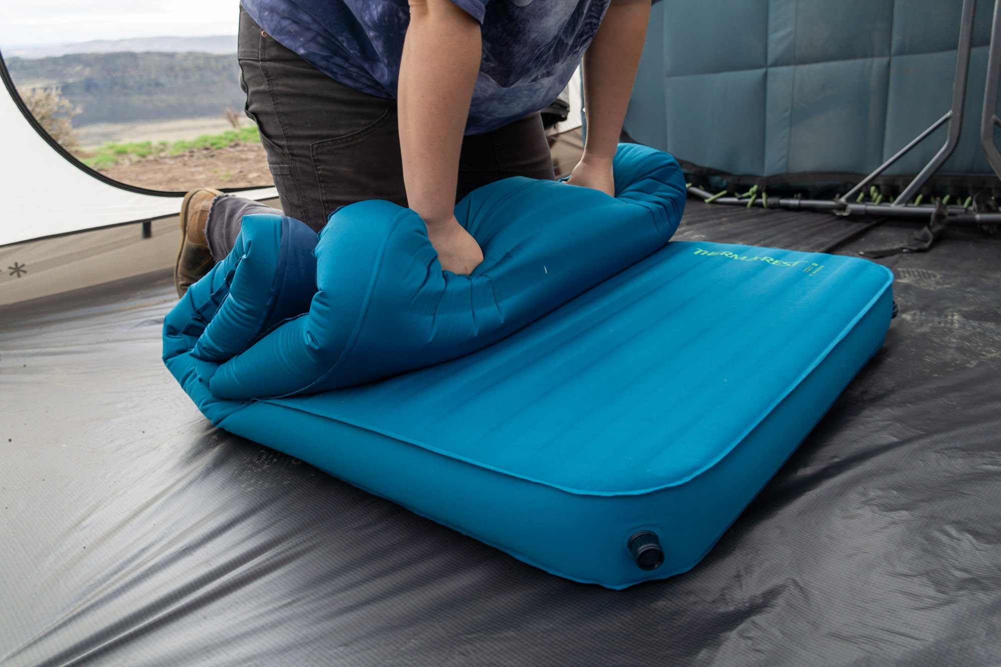 A camper leaning on the mattress to force air out through the TwinLock valves.