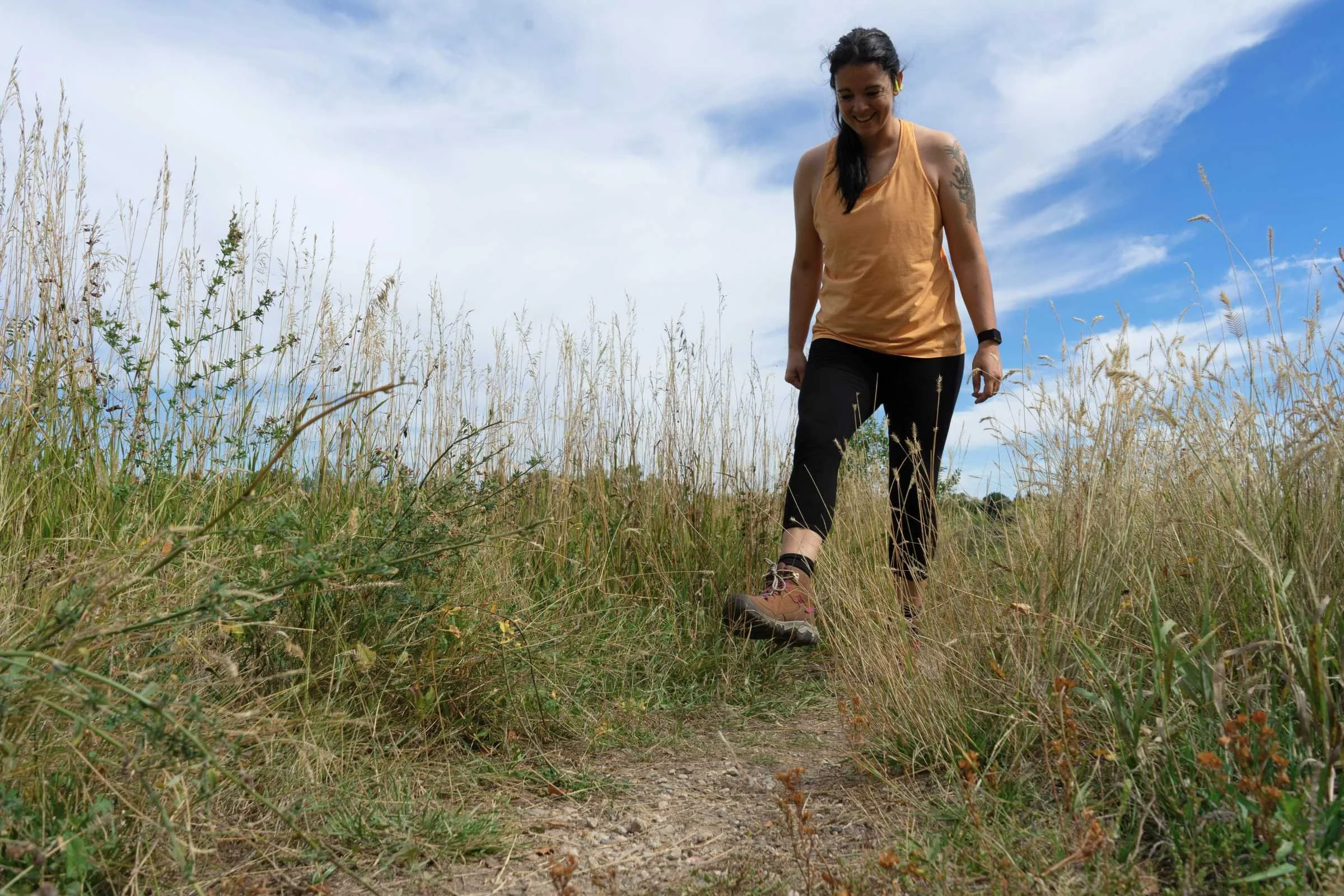 A hiker walking on a dirt trail wearing Keen hiking boots.