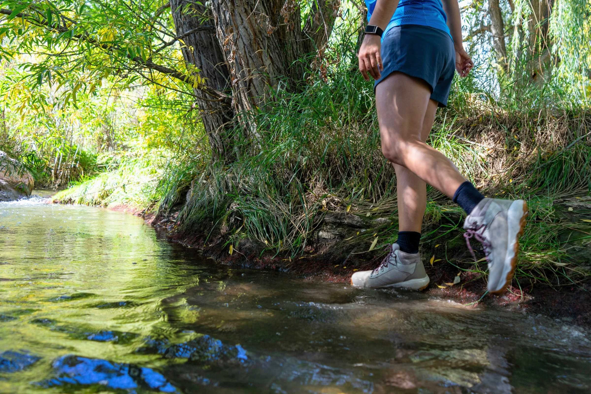 A hiking boot submerged in shallow creek water to test its waterproof membrane.