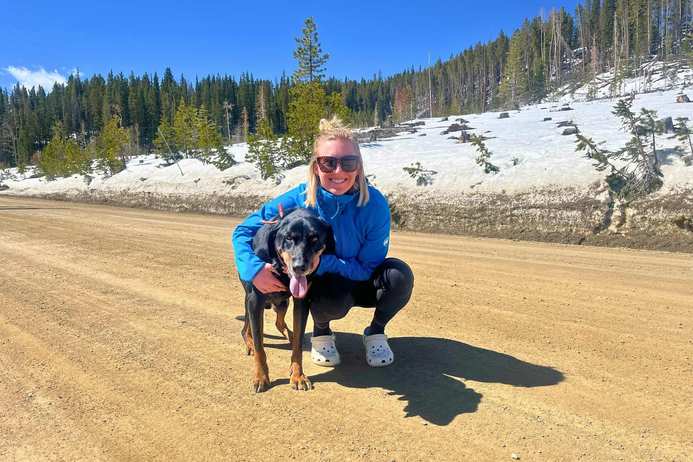 A hiker wearing a softshell jacket while trekking through spring snow in the mountains.