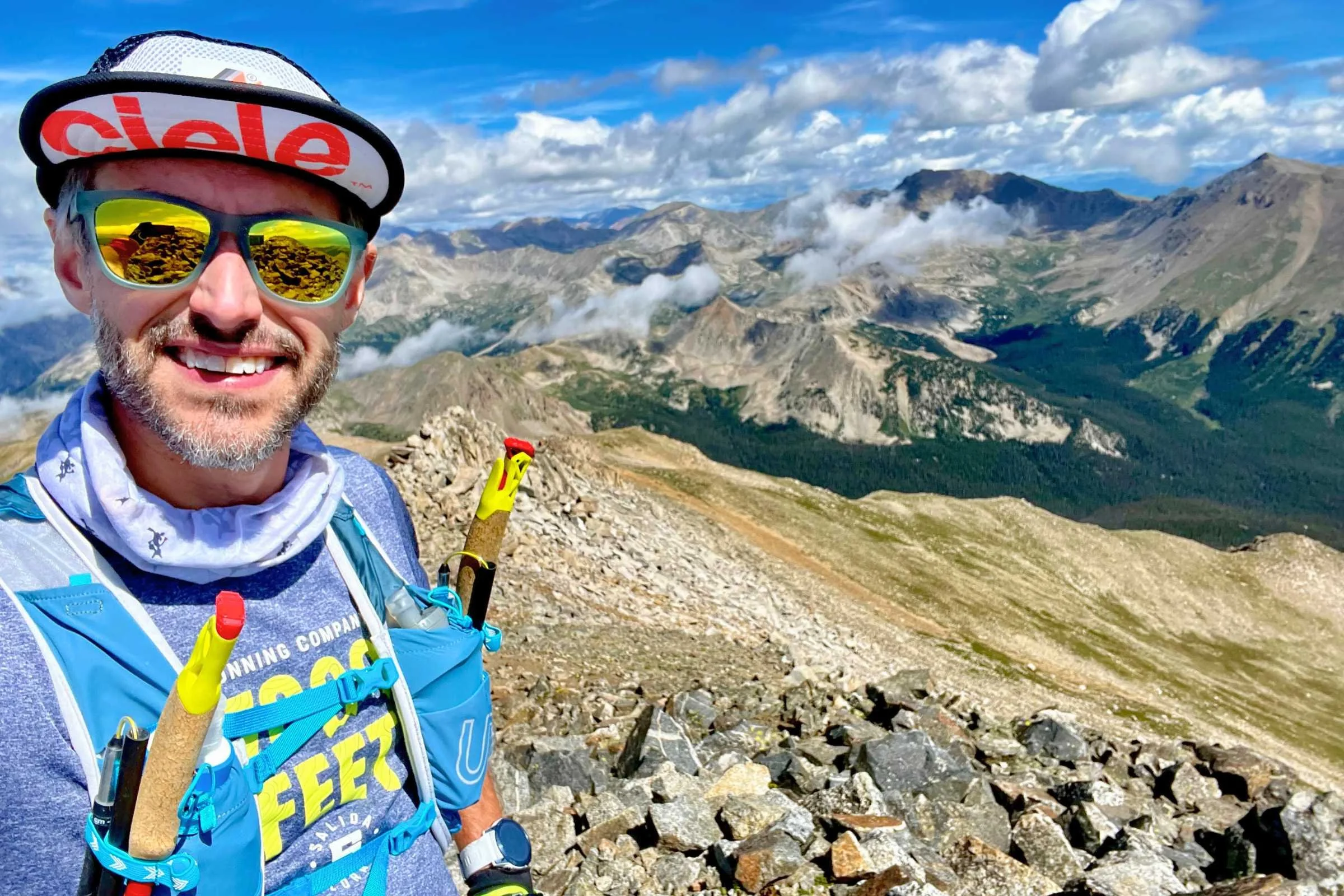 A runner on a rocky mountain peak wearing Goodr OG sunglasses with mirrored lenses.