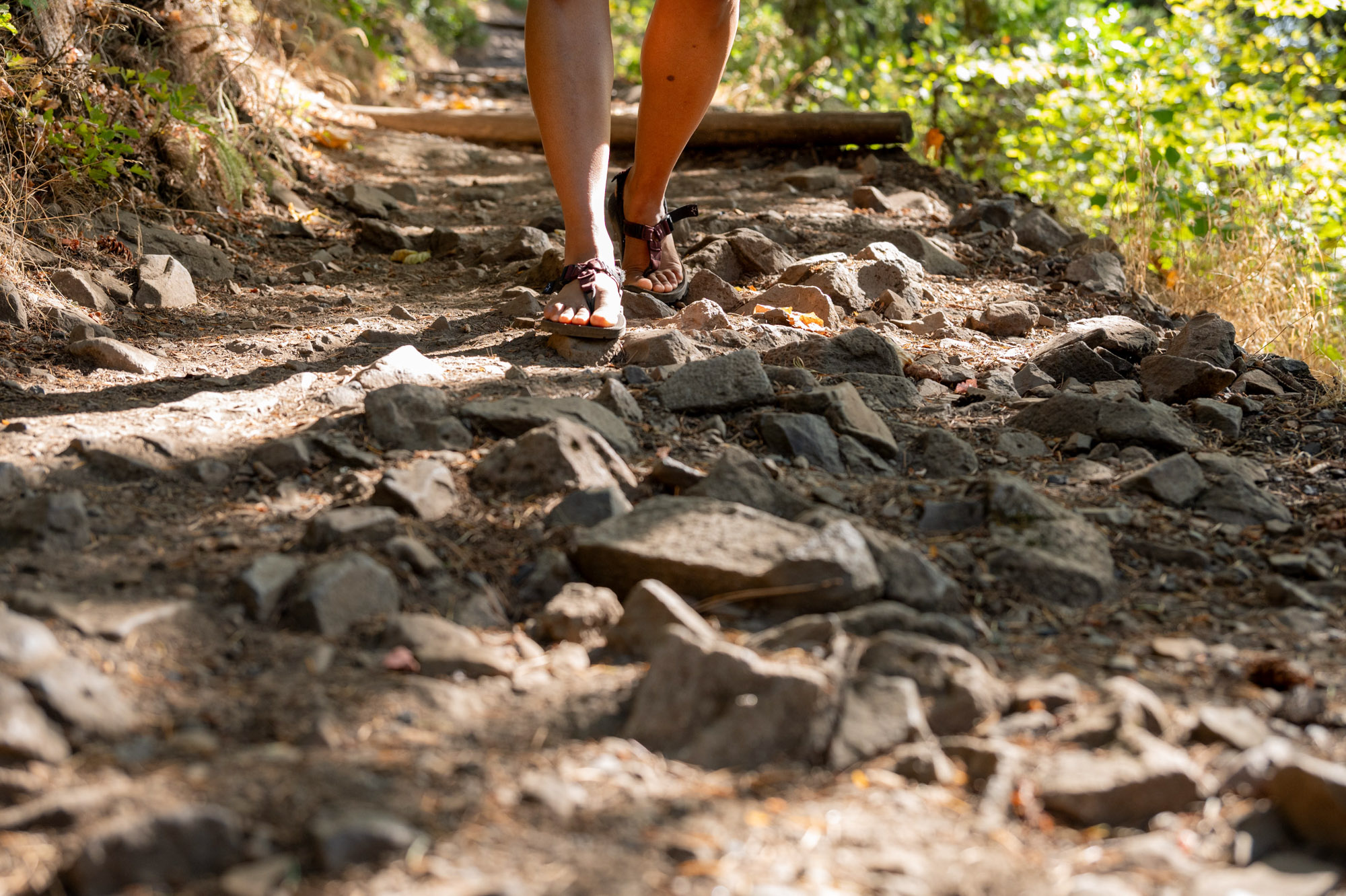A hiker wearing Bedrock Cairn Evo sandals descending a steep, rocky trail.
