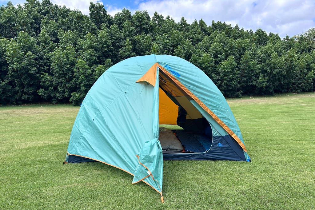 A blue and gray Kelty Wireless 6-person tent set up in a wooded area.