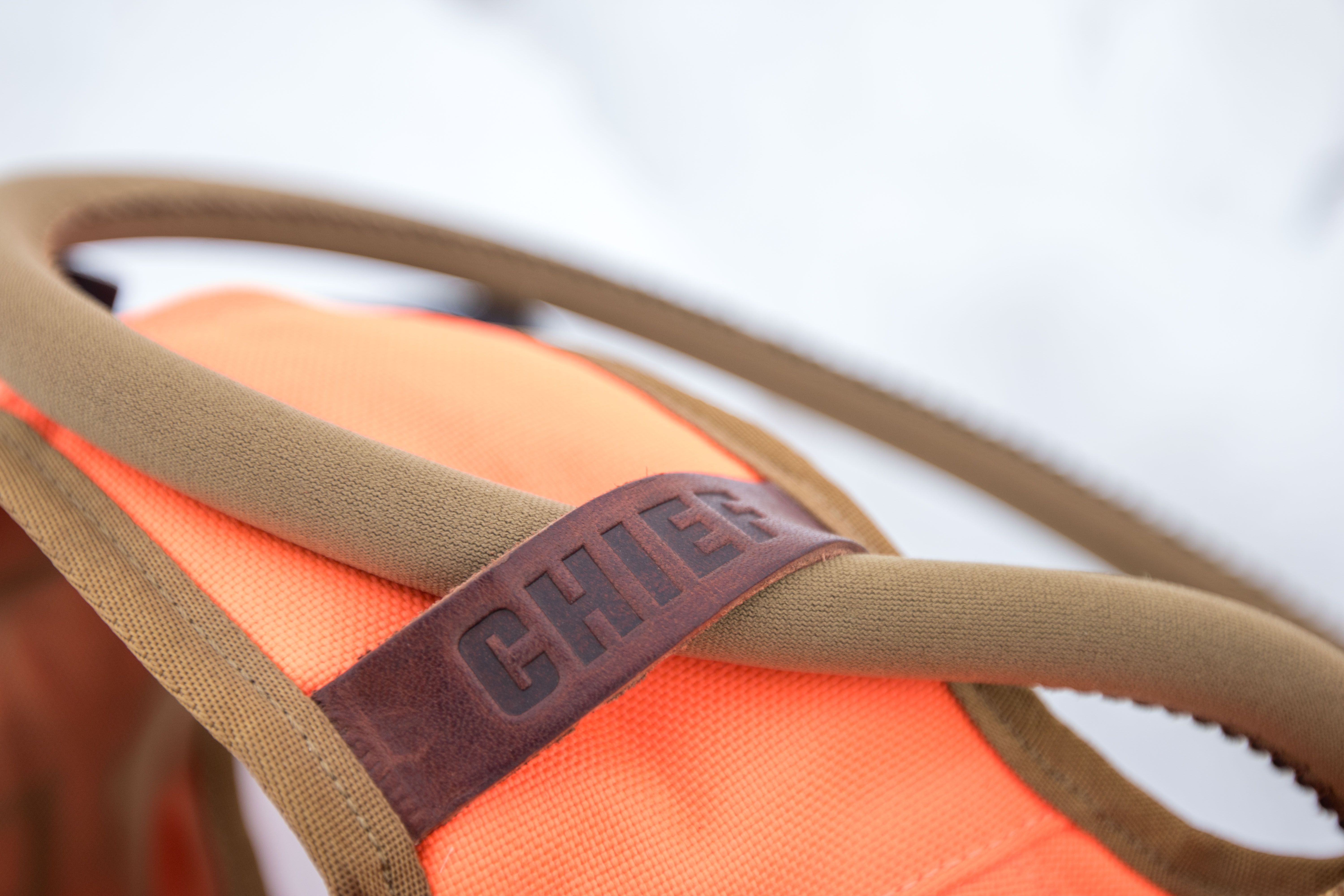 A hydration tube threaded through a leather guide on the vest strap.