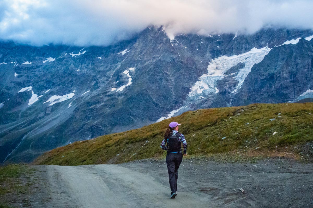 A runner navigating a road in the Italian Alps during a cold rain shower.