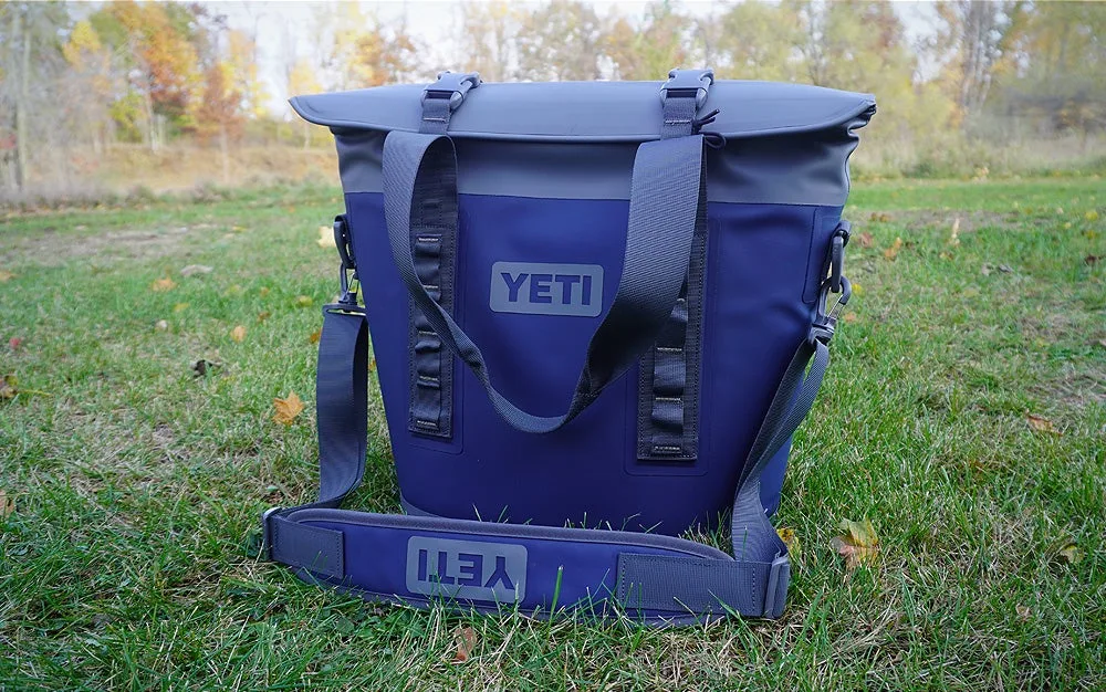 Dark blue Yeti M15 magnetic soft cooler on a grassy lawn.