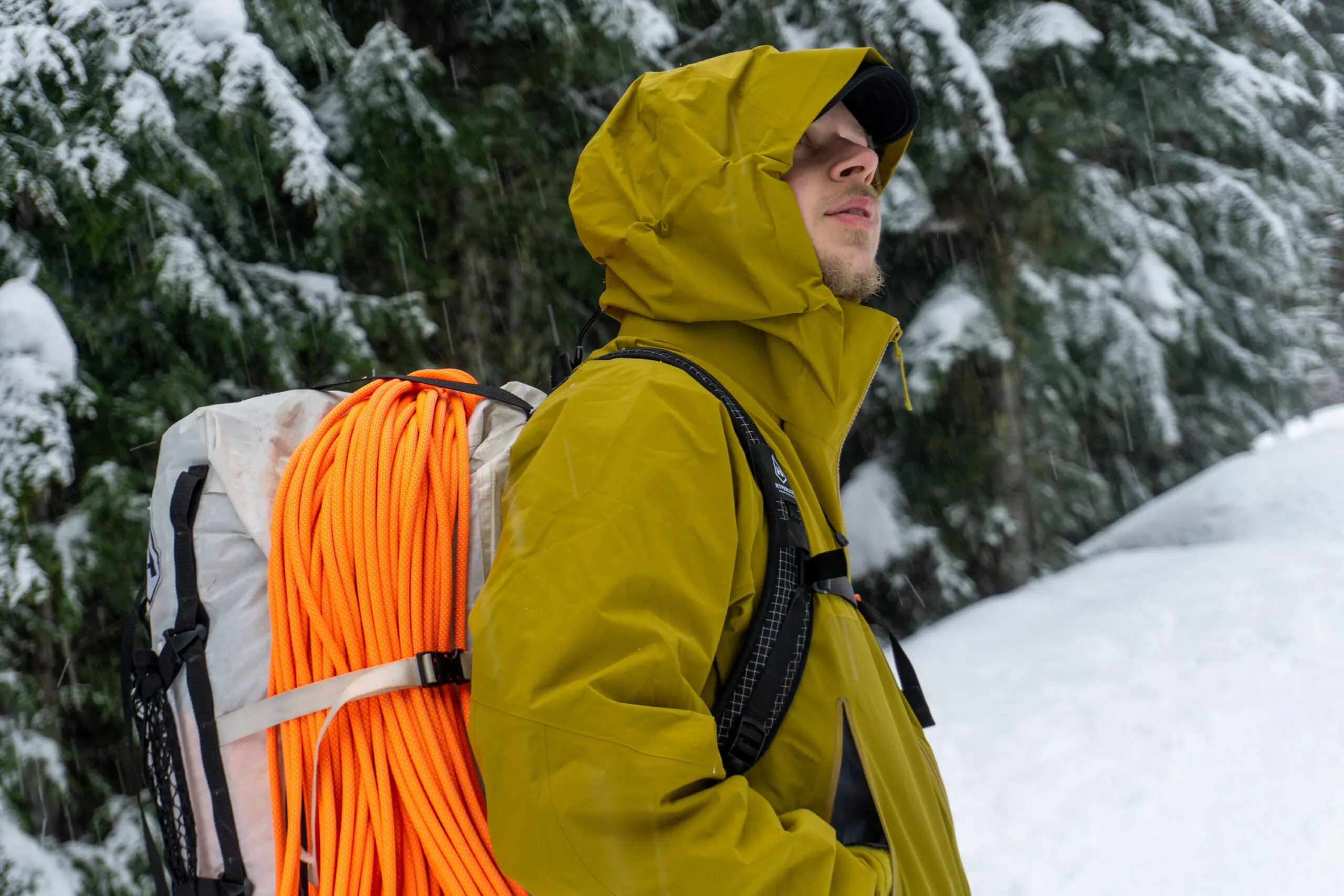 A hiker wearing a premium red hardshell jacket overlooking a mountain range.