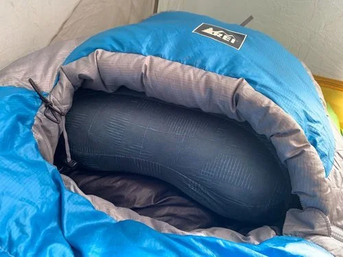 A Therm-a-Rest Air Head Down pillow nestled perfectly into the hood of a green mummy-style sleeping bag.