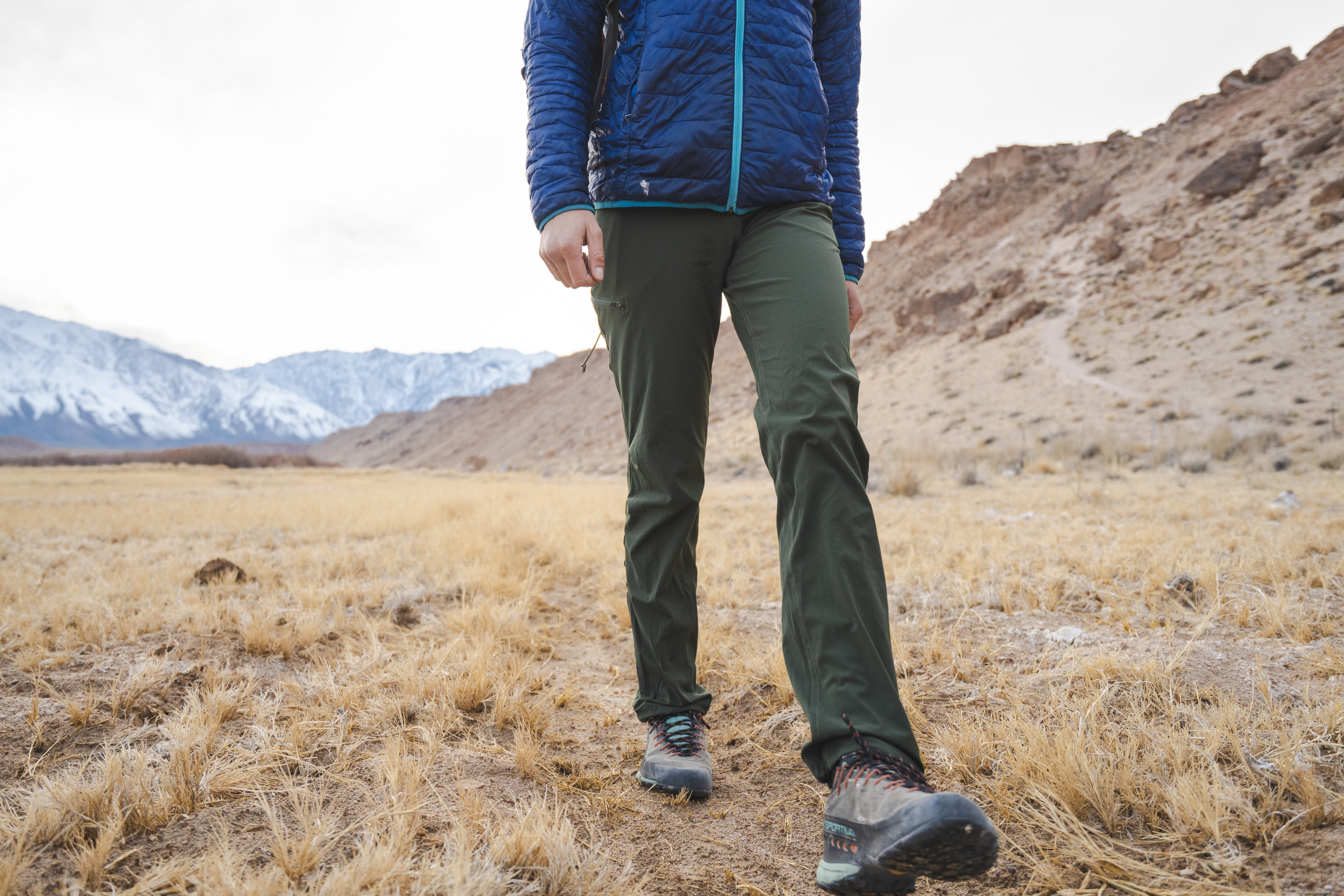 A hiker demonstrates the flexibility and articulation of hiking pants during a high-step movement.