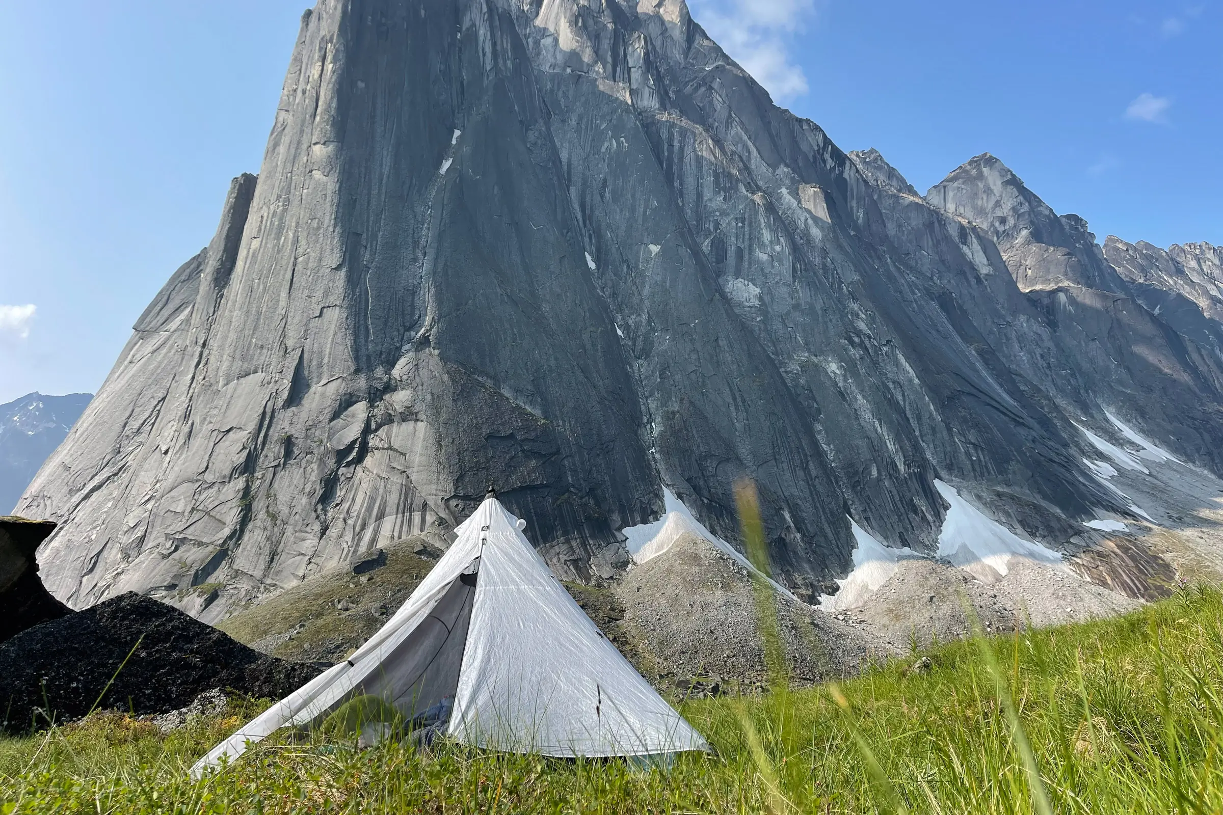 A white Hyperlite Mountain Gear Ultamid 4 pyramid shelter in a remote mountain meadow.