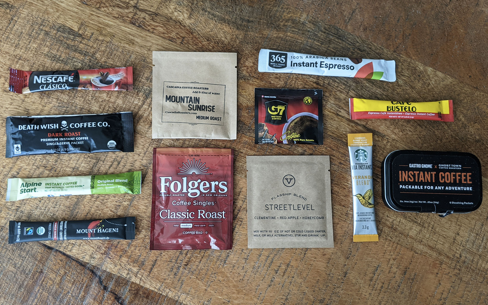 A wide variety of instant coffee packets and brands laid out on a table for a side-by-side comparison test.
