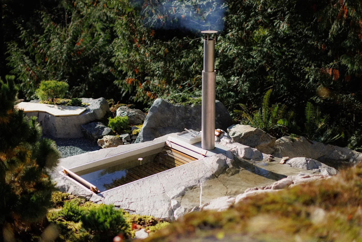 The Goodland x Wavestone wood-fired rock hot tub installed in a natural landscape.