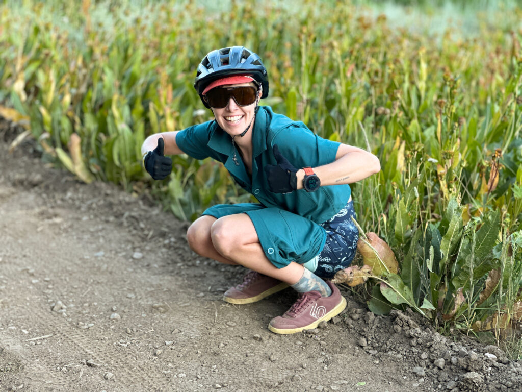 A person in hiking gear demonstrating a squat on a forest trail.