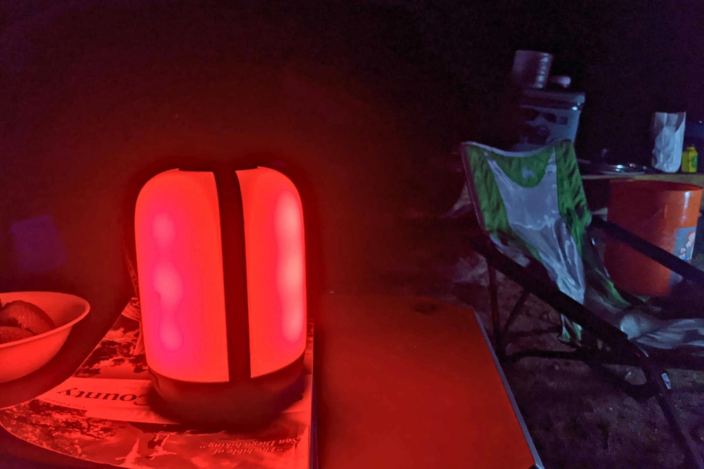 The BioLite AlpenGlow lantern emitting a soft red glow inside a dark camping tent.