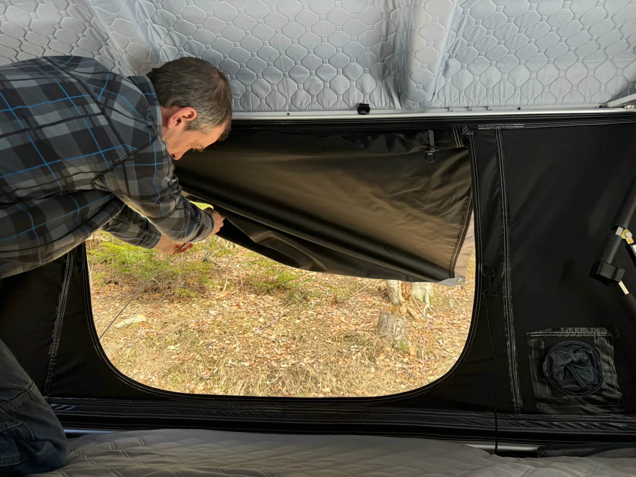 A rooftop tent fully deployed on a vehicle parked in a remote, rugged landscape.
