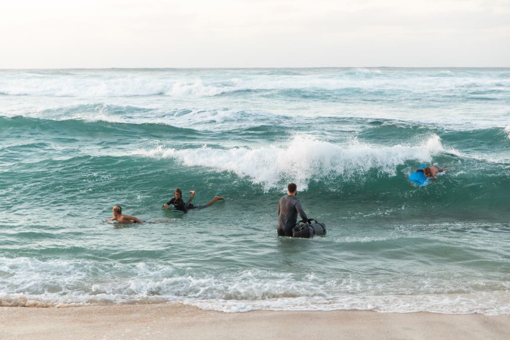 Person carrying a Yeti duffel bag while wading in the ocean.